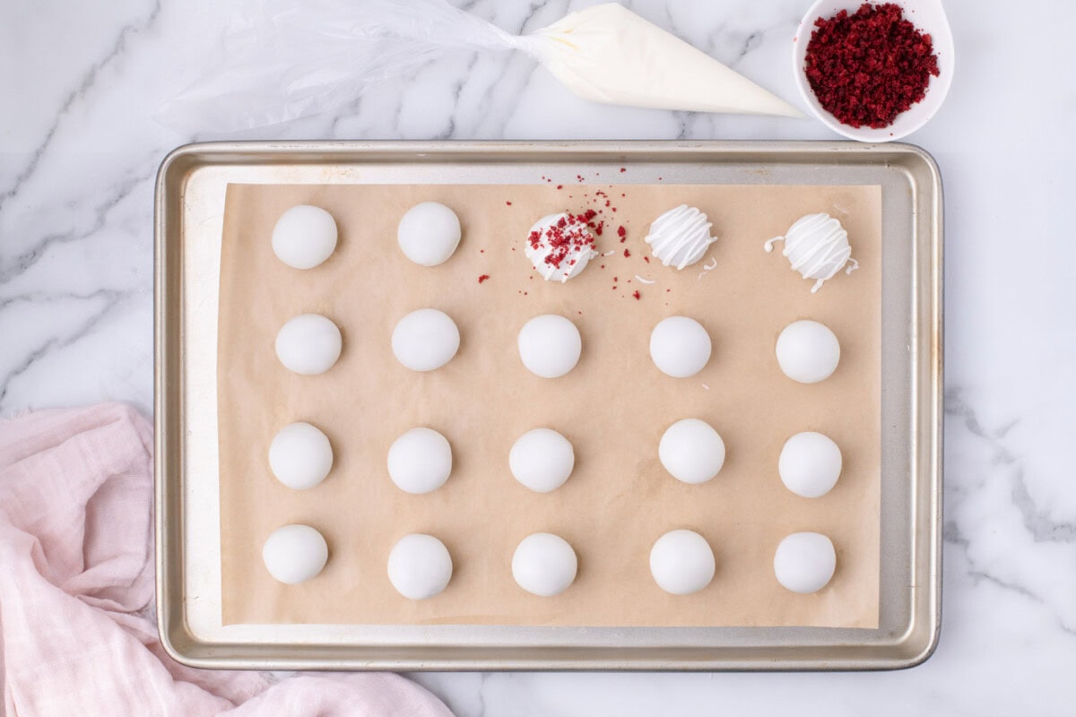 sprinkling cake crumbles on top of red velvet cake balls