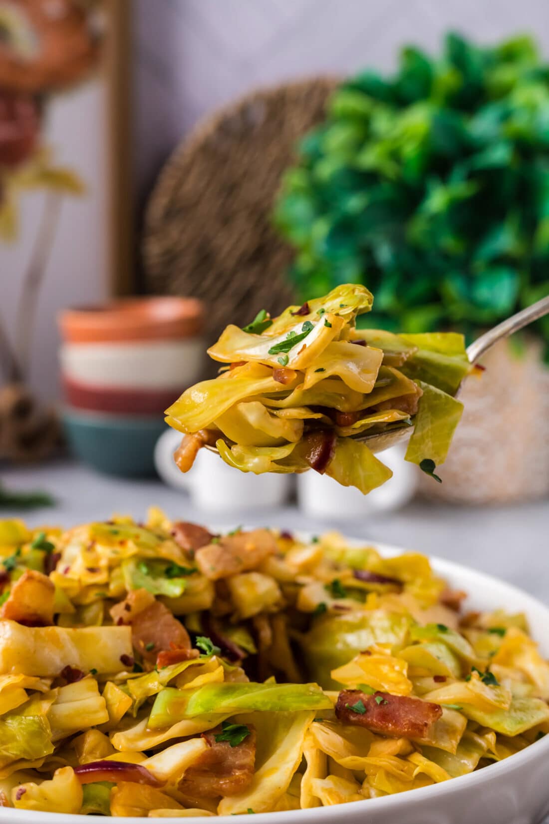 Spoonful of Spicy Fried Cabbage held above a bowl of Spicy Fried Cabbage