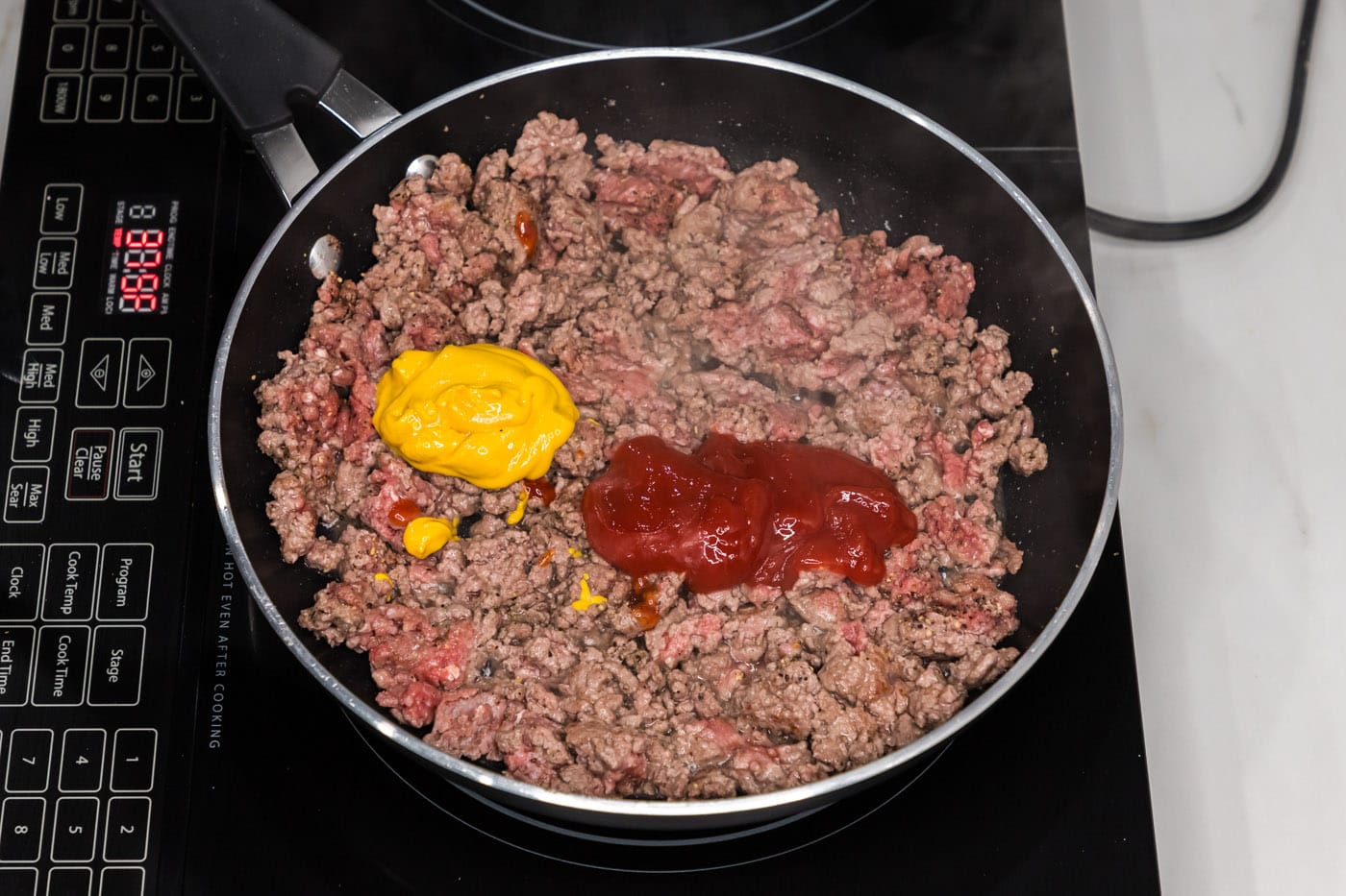mustard and ketchup added to ground beef in skillet