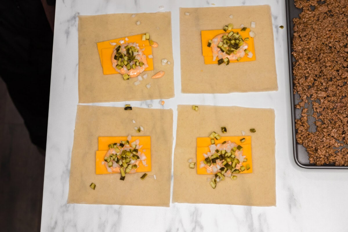 egg roll wrappers with cheddar cheese, onion, and pickles