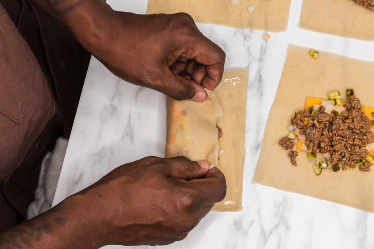 hands rolling egg roll wrapper