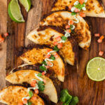 Close up photo of Black Bean Tacos on a wooden platter topped with sour cream, tomatoes and cilantro