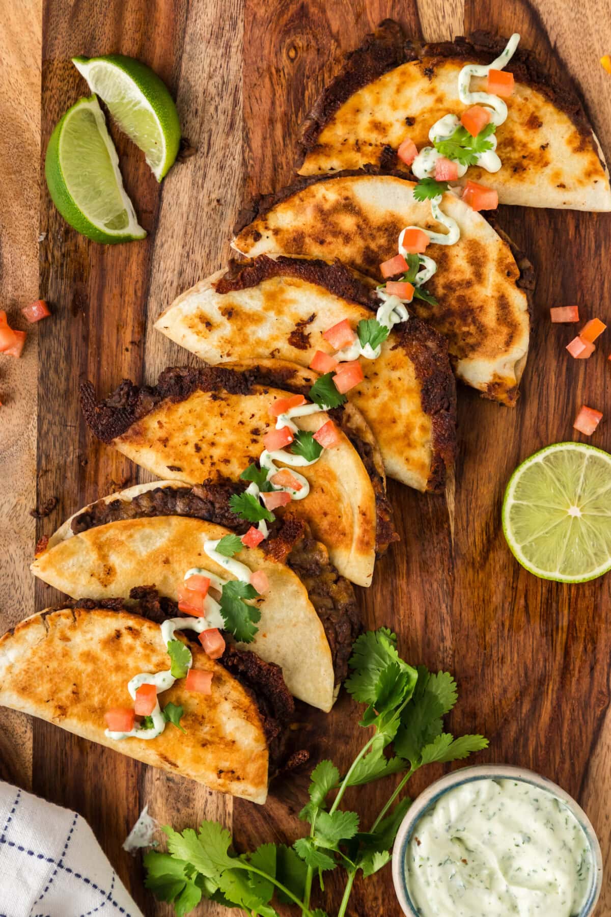 Black Bean Tacos on a wooden board topped with sour cream, tomatoes and cilantro