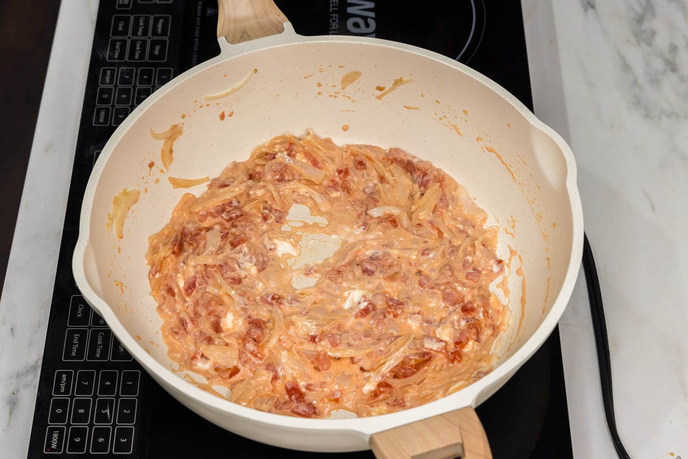 cream cheese stirred into tomatoes and onions in a skillet