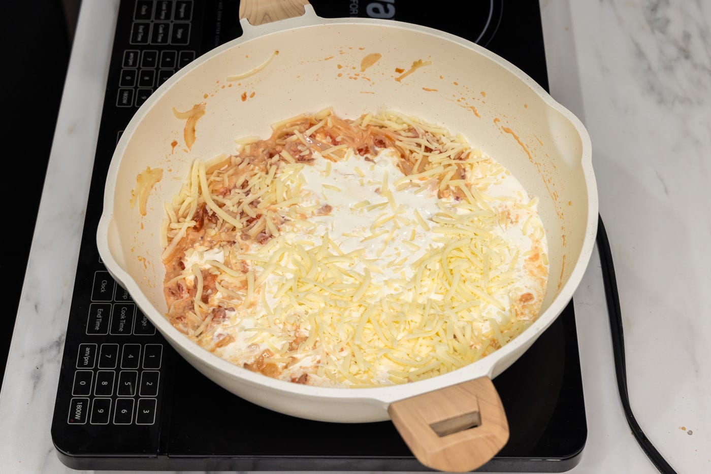 heavy cream added to skillet with cheese, tomatoes, and cream cheese