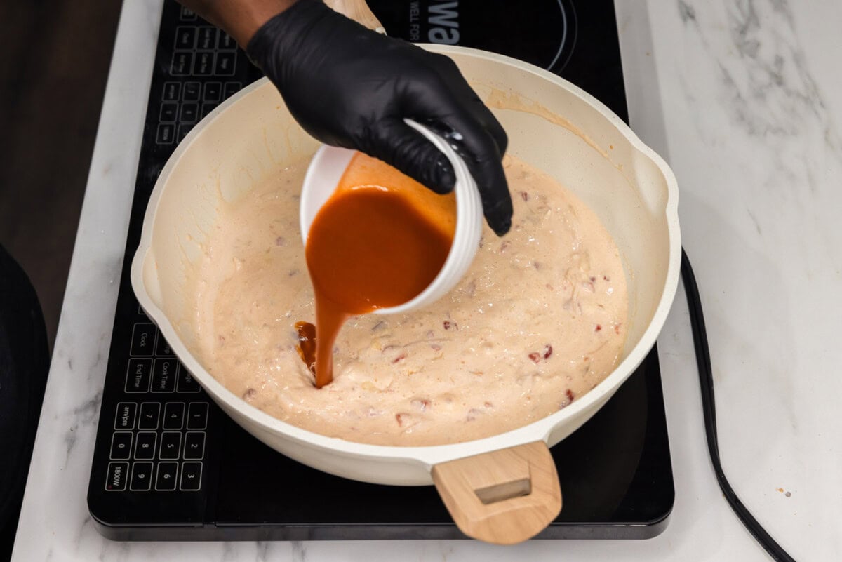 pouring hot sauce into skillet with cream cheese mixture