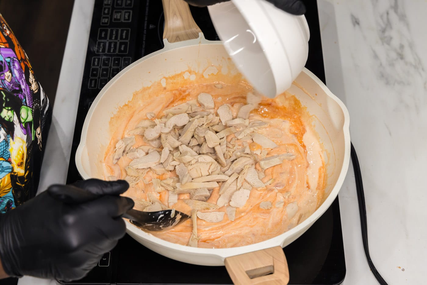 stirring chicken into skillet with creamy buffalo sauce