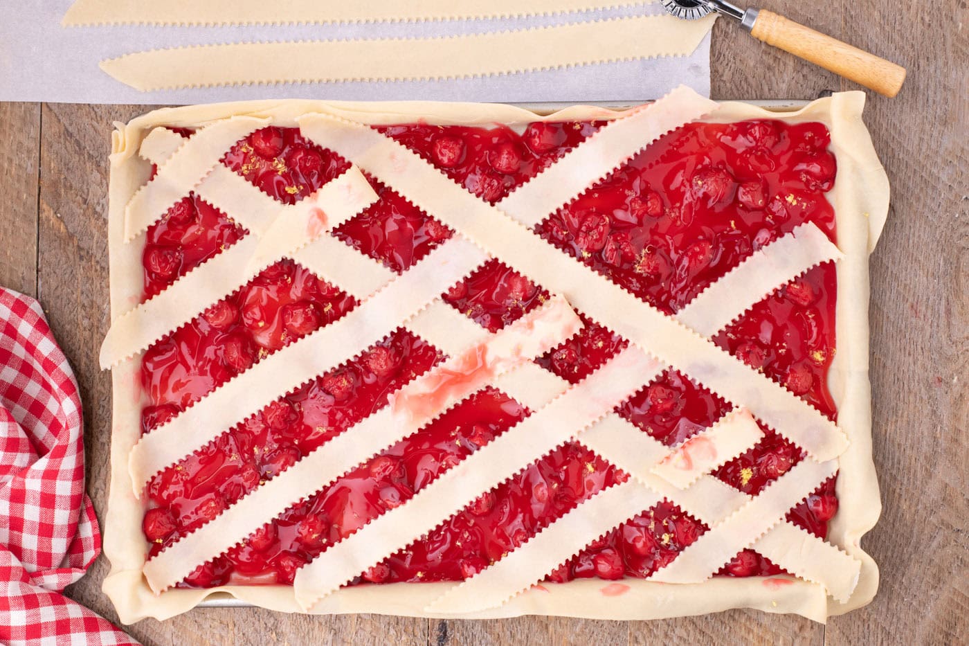 arranging pie crust weave on top of cherry pie filling