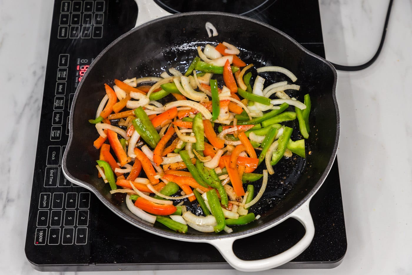sliced bell peppers and onion sauteed in a skillet