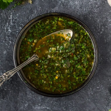 Close up photo of a bowl of Chimichurri with a spoon in it