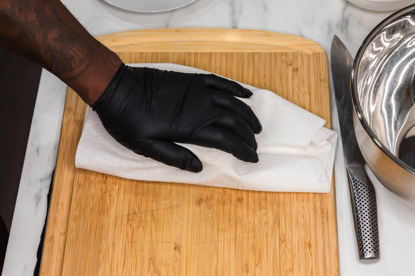 hand squeezing out excess moisture from tofu with a paper towel