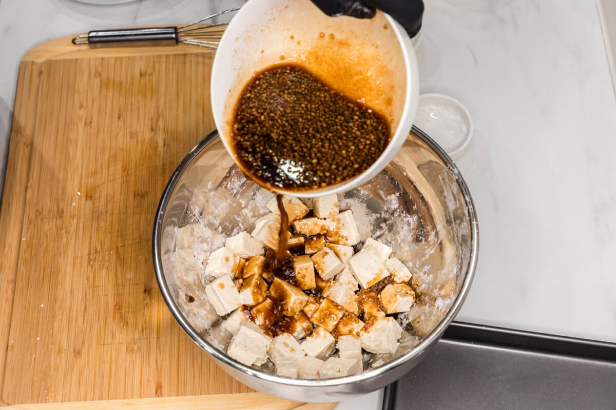 pouring sauce over cornstarch coated tofu cubes