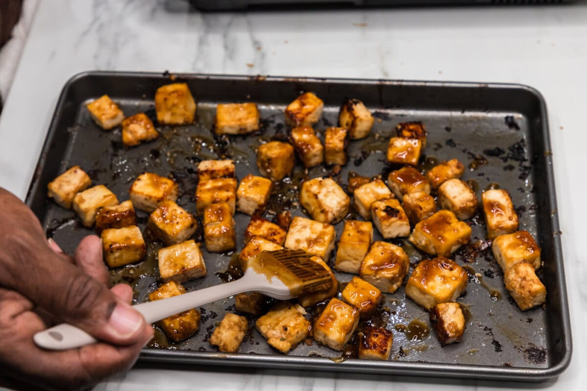 brushing tofu cubes with honey garlic sauce