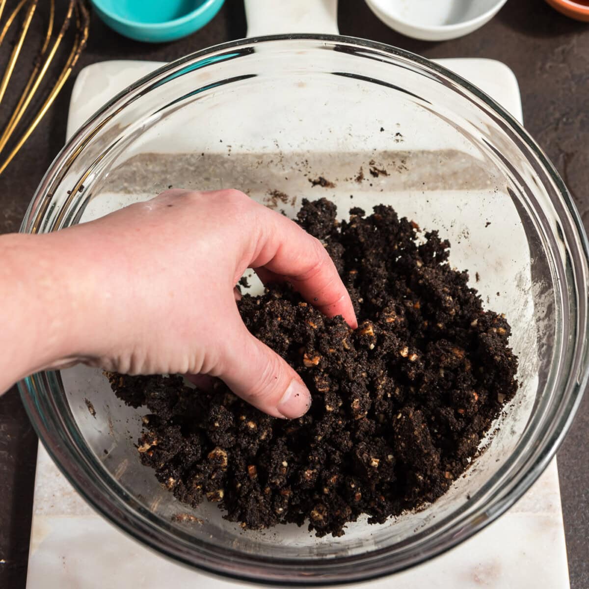 hand fluffing pecan and chocolate graham cracker crust in a bowl