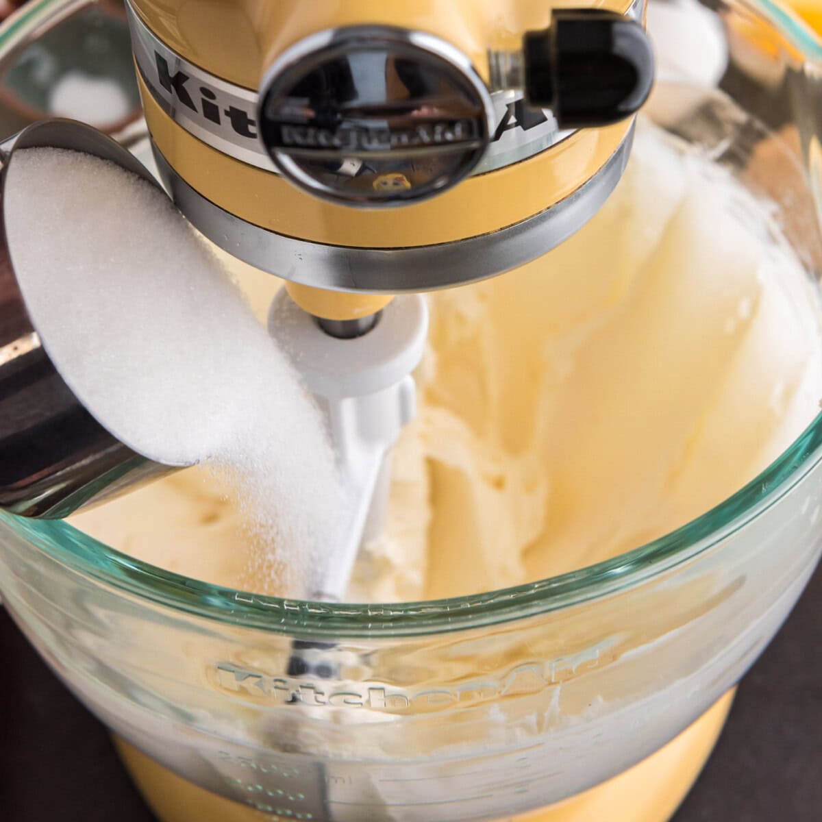 pouring sugar into bowl of whipped cream cheese