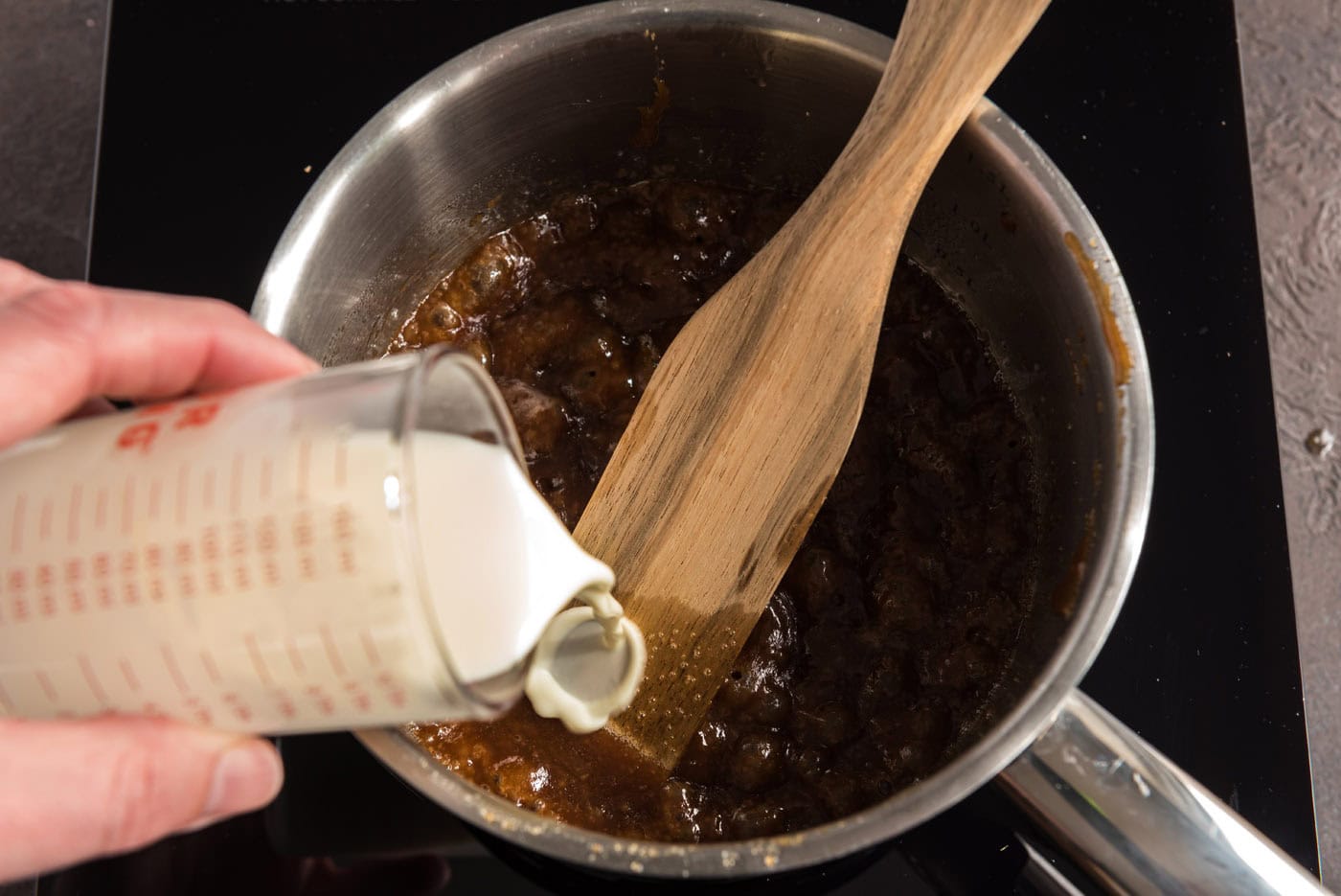 pouring heavy cream into sauce pan with brown sugar and butter