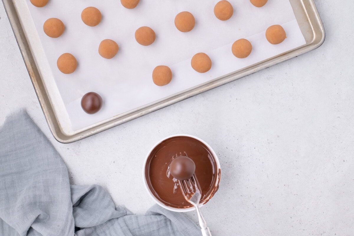 dipping nutter butter cookie ball into chocolate with a fork