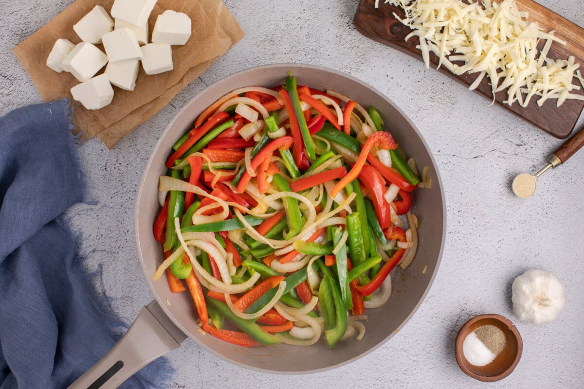 sliced bell peppers and onions in a skillet