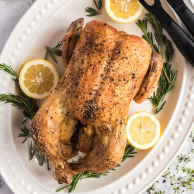 Close up photo of a Roasted Chicken on a white platter
