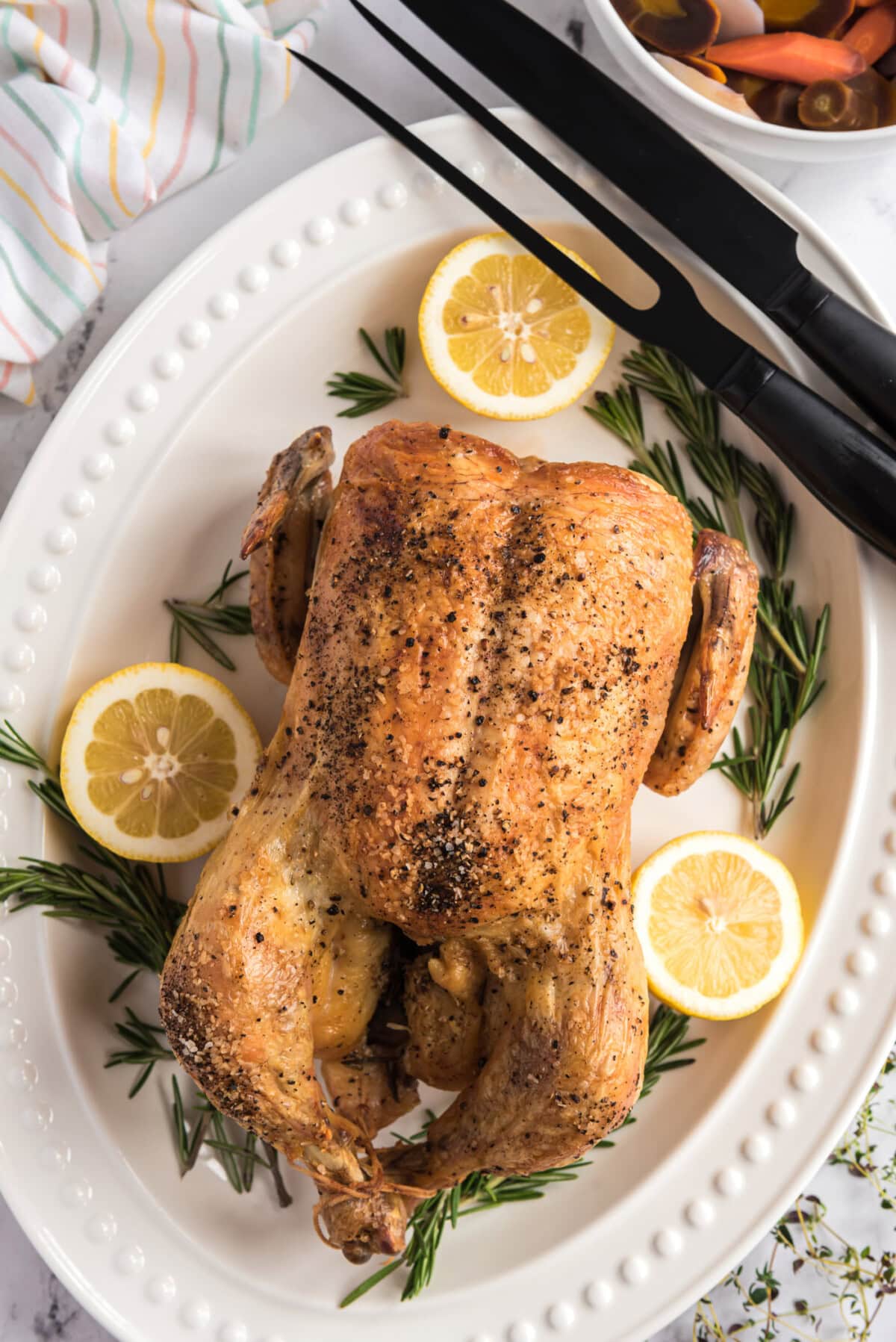 Roasted Chicken on a platter with carving utensils to the side