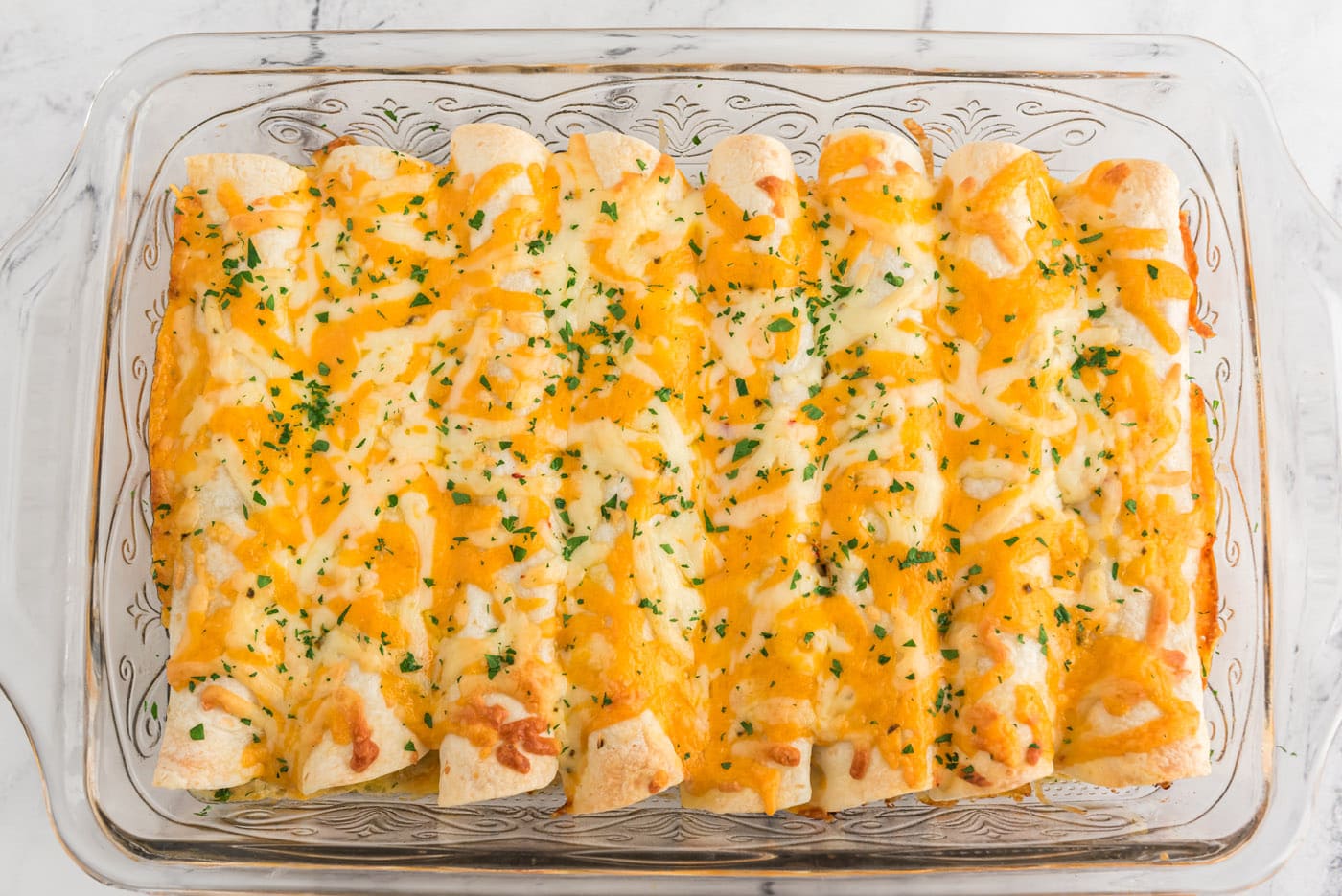baked shredded chicken and chile enchiladas in a baking dish