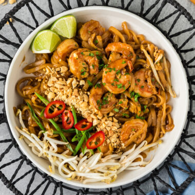 Bowl of Shrimp Pad Thai with chopped peanuts, bean sprouts, green onion and pepper on the side