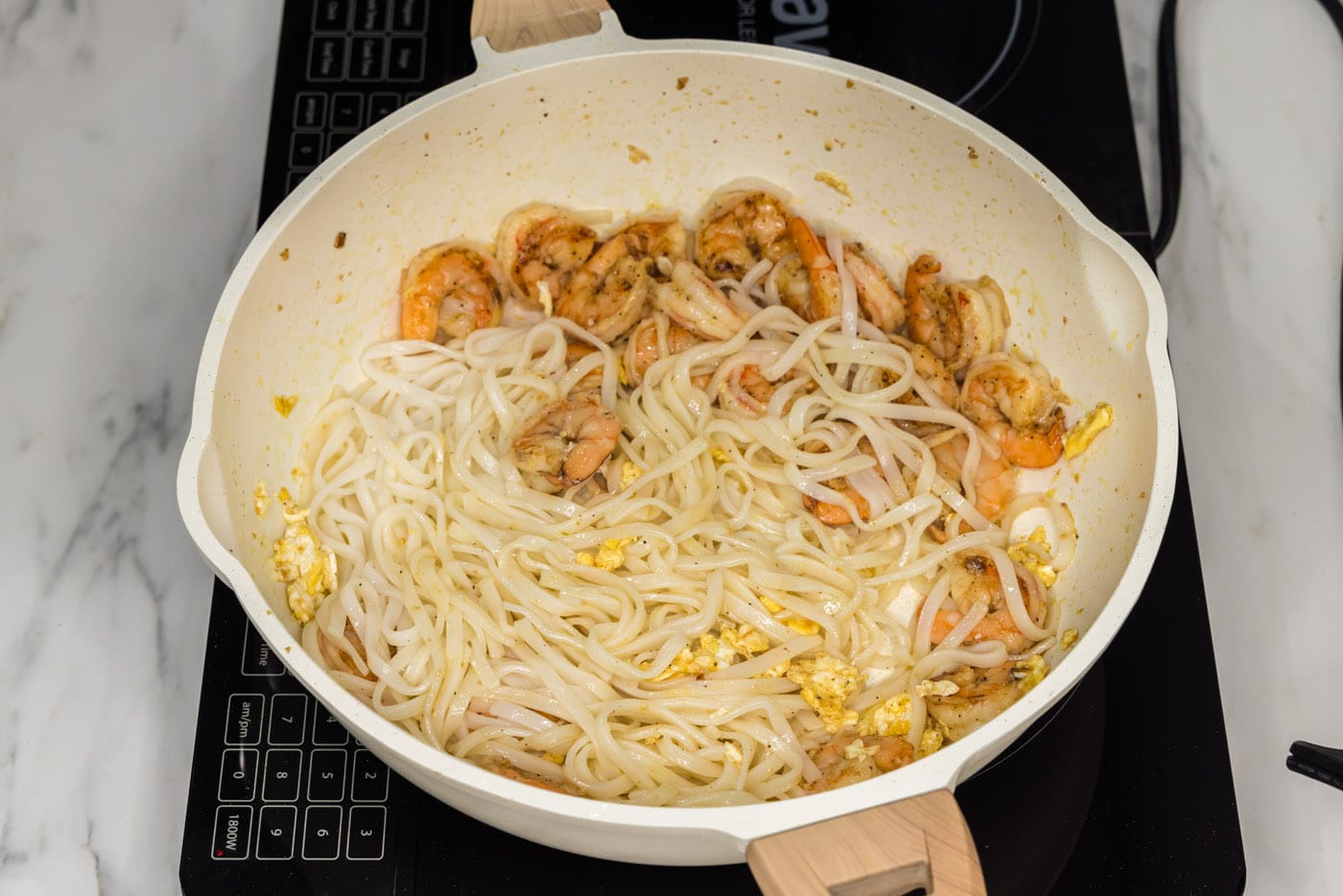 cooked rice noodles added to skillet with shrimp and egg
