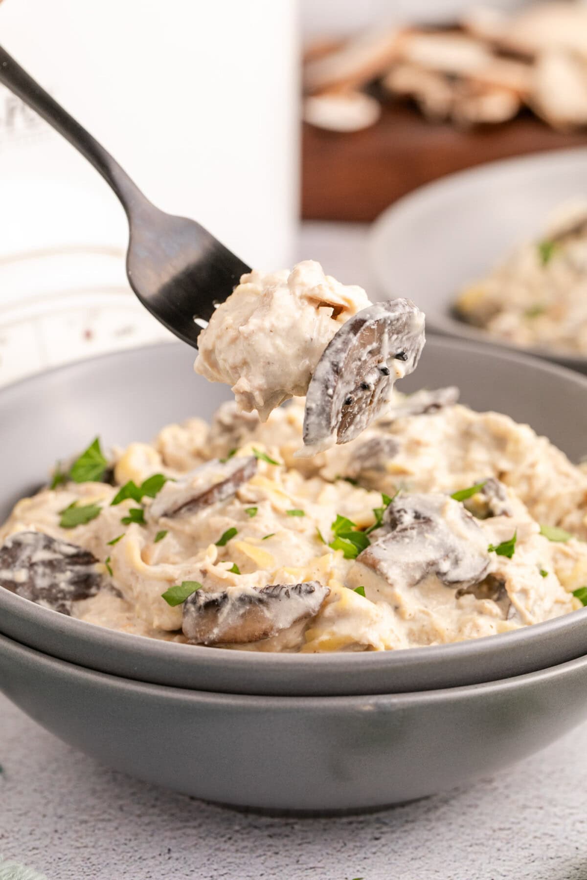 Slow Cooker Chicken Stroganoff on a fork held above a bowl of Slow Cooker Chicken Stroganoff