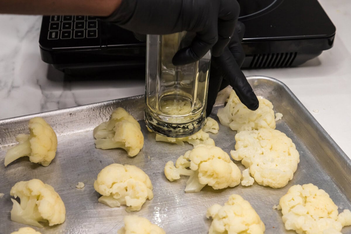 smashing cauliflower florets with the flat end of a drinking glass