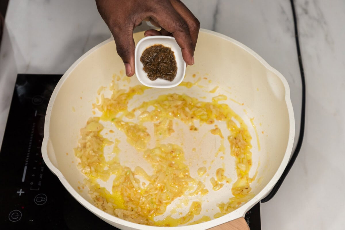 adding bouillon base to skillet with onion and garlic