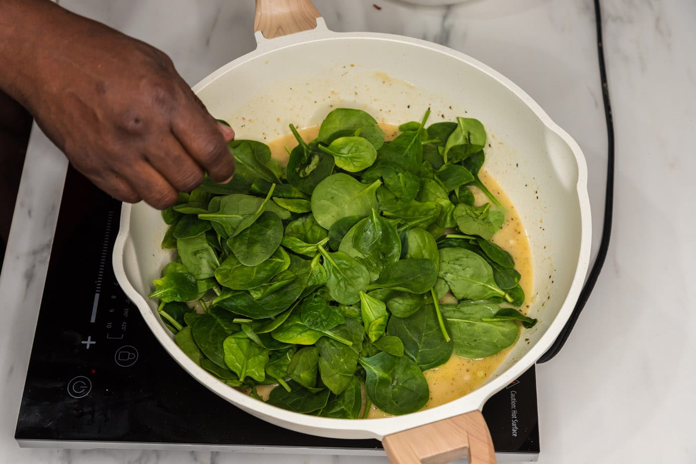 spinach leaves in a skillet over pasta sauce