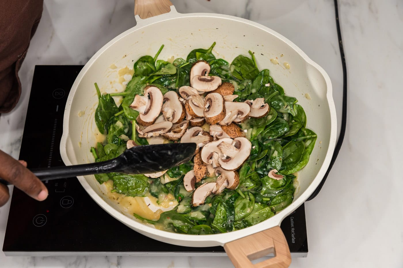 sliced mushrooms on top of spinach and sauce in a skillet