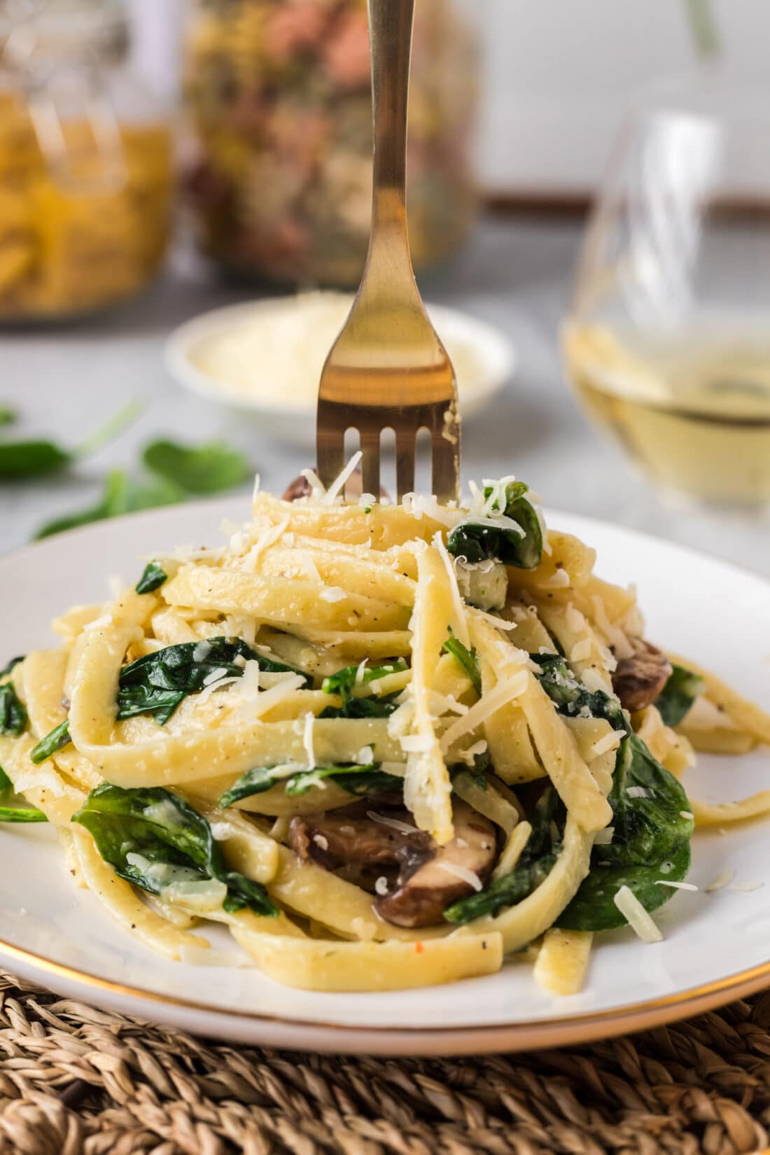Fork stuck inside a heaping portion of Spinach Fettuccine on a plate