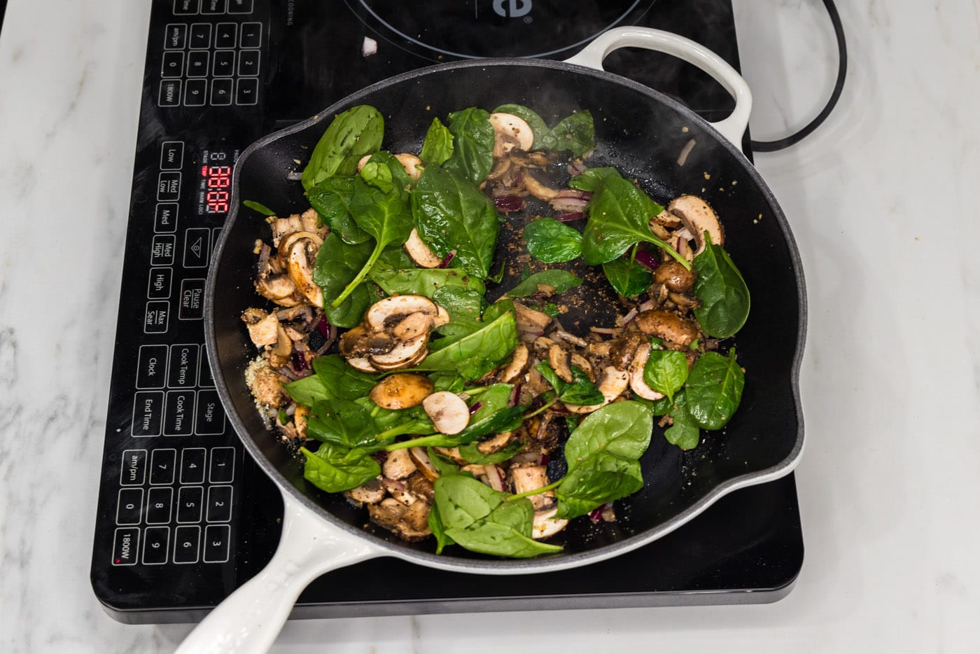 fresh spinach leaves added to skillet with mushrooms and onion