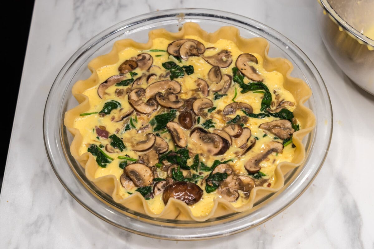 layer of spinach and mushrooms over egg filling in a pie plate