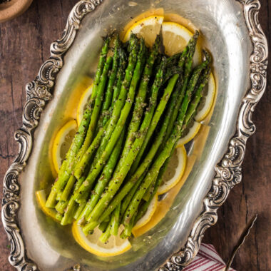 Steamed Asparagus resting on lemon slices on a platter