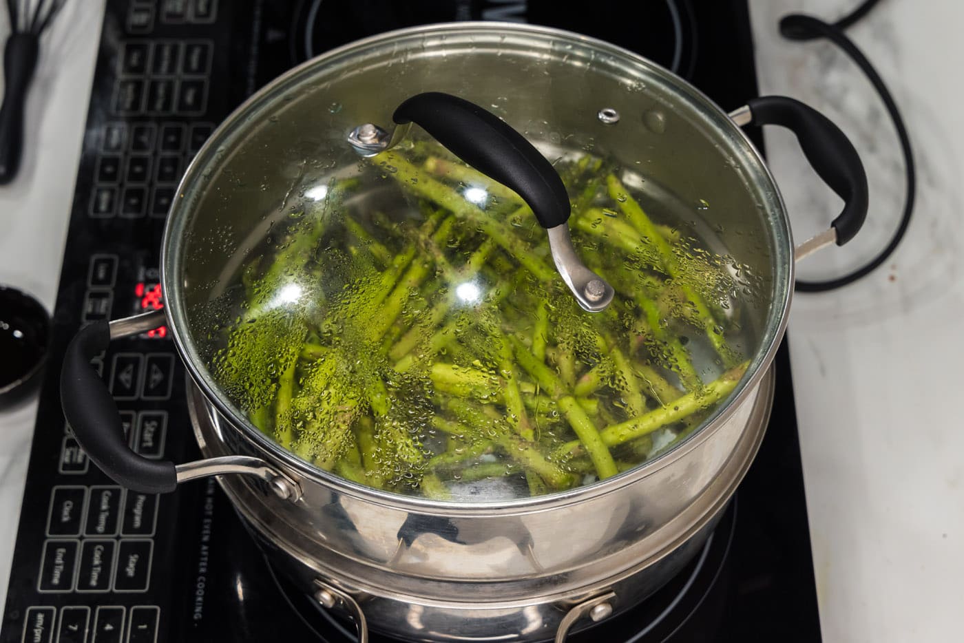 lid covering asparagus spears in a steam pot