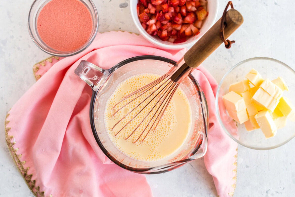 Buttermilk, eggs, and vanilla in measuring cup with a whisk