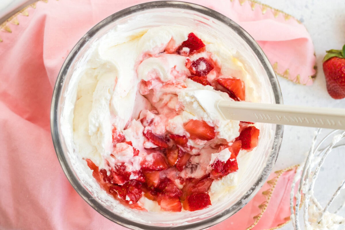 Crushed strawberries being mixed into the frosting mixture