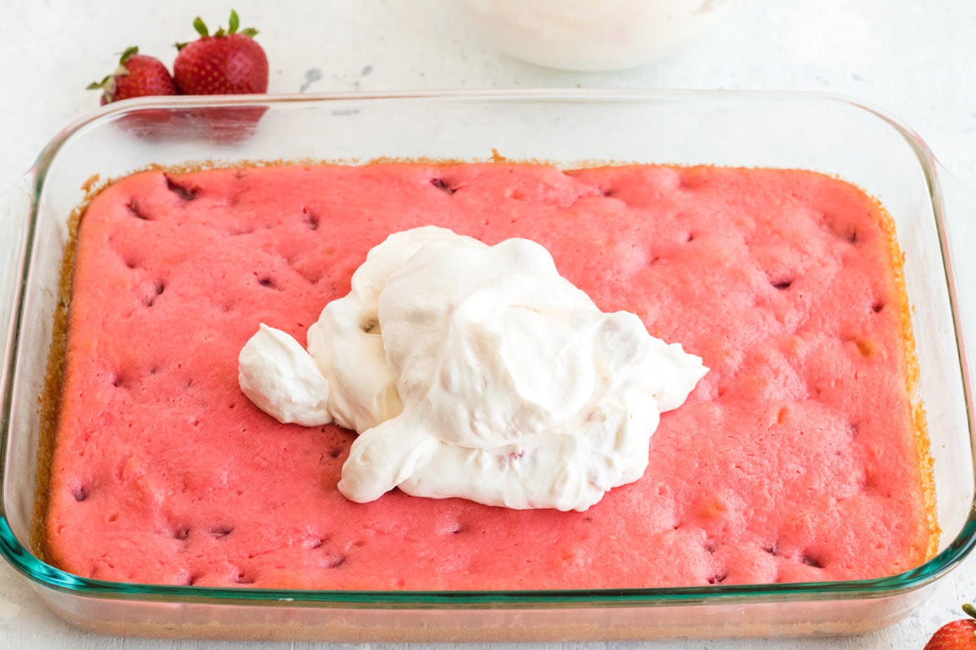 Frosting being spread on top of strawberry cake