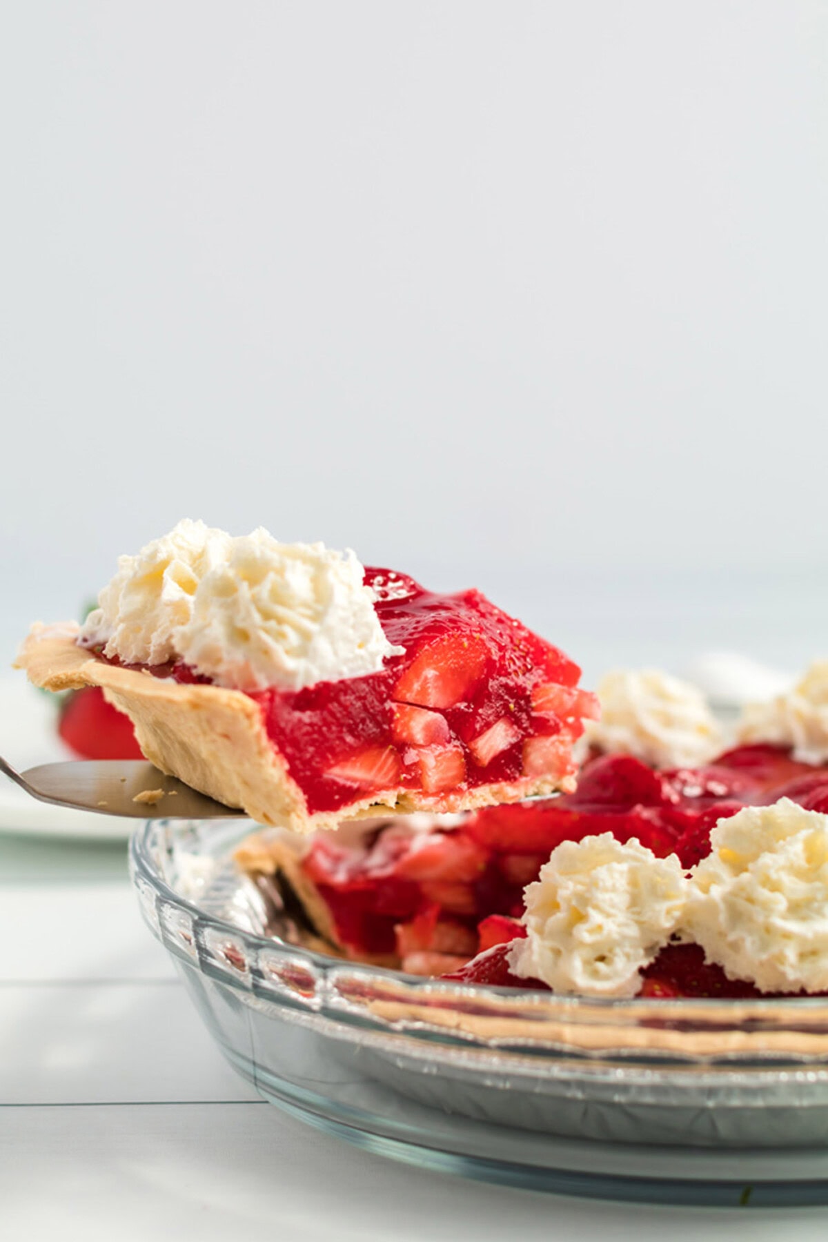 slice of strawberry pie being taken from the pie plate