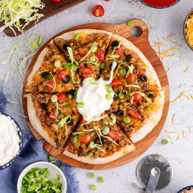 Taco Pizza cut into slices topped with sour cream