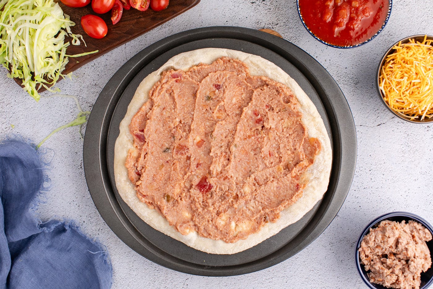 layer of refried beans and salsa over pizza crust