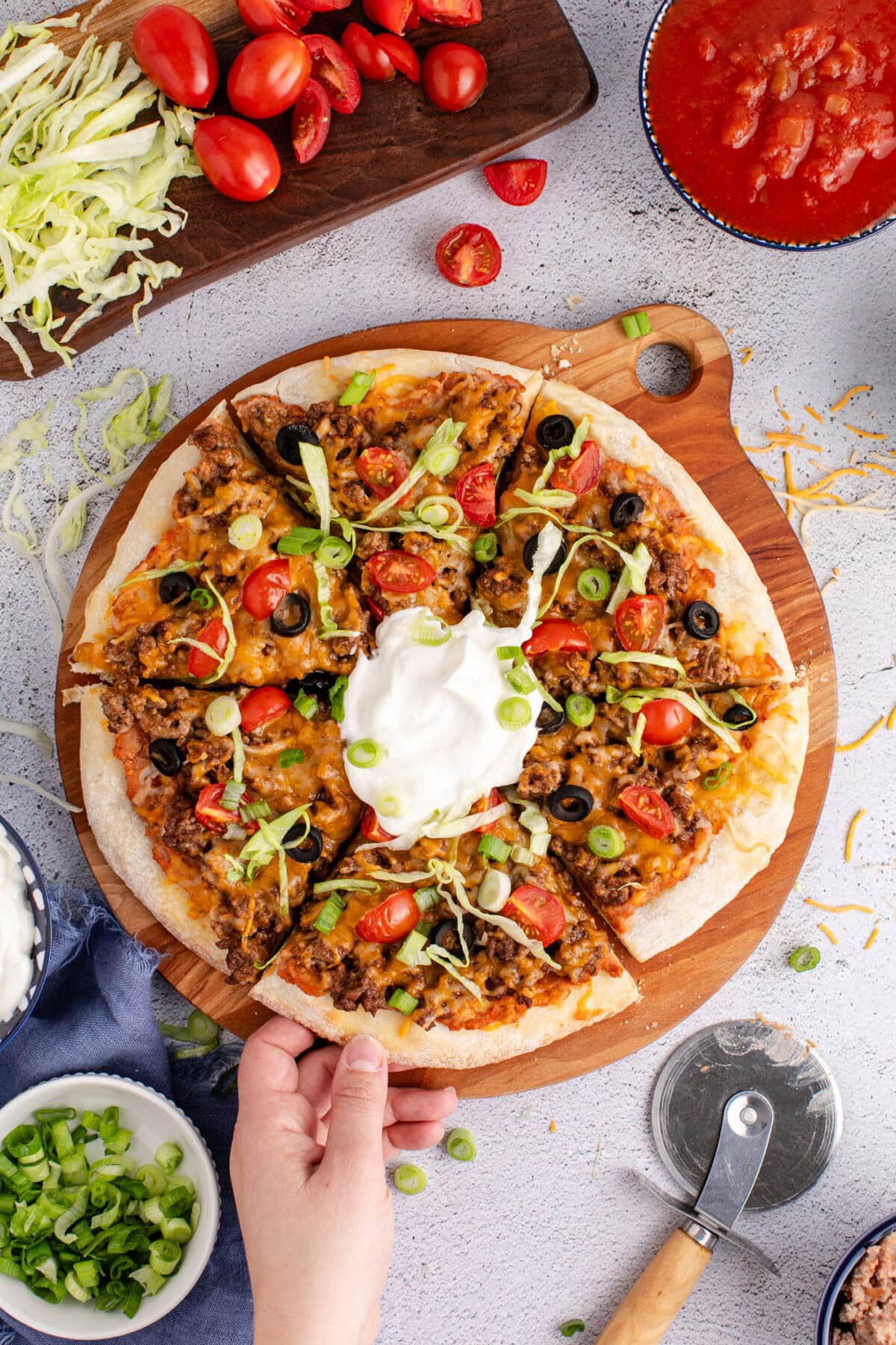 Hand grabbing a slice of Taco Pizza