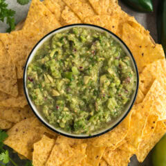 Bowl of Tomatillo Onion Avocado Salsa surrounded by tortilla chips
