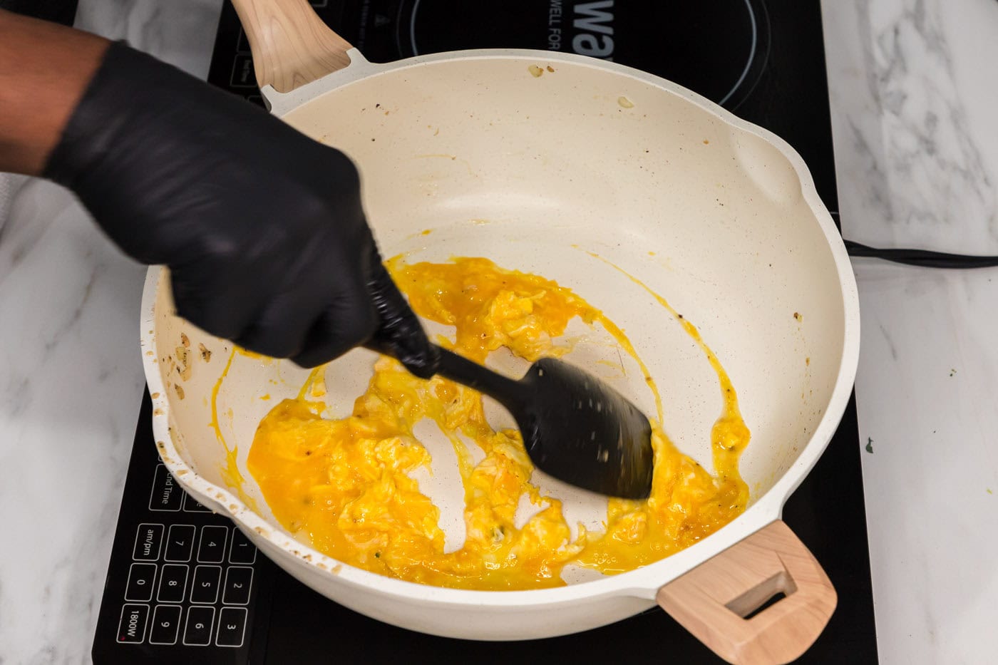 scrambling eggs in a skillet with a rubber spatula