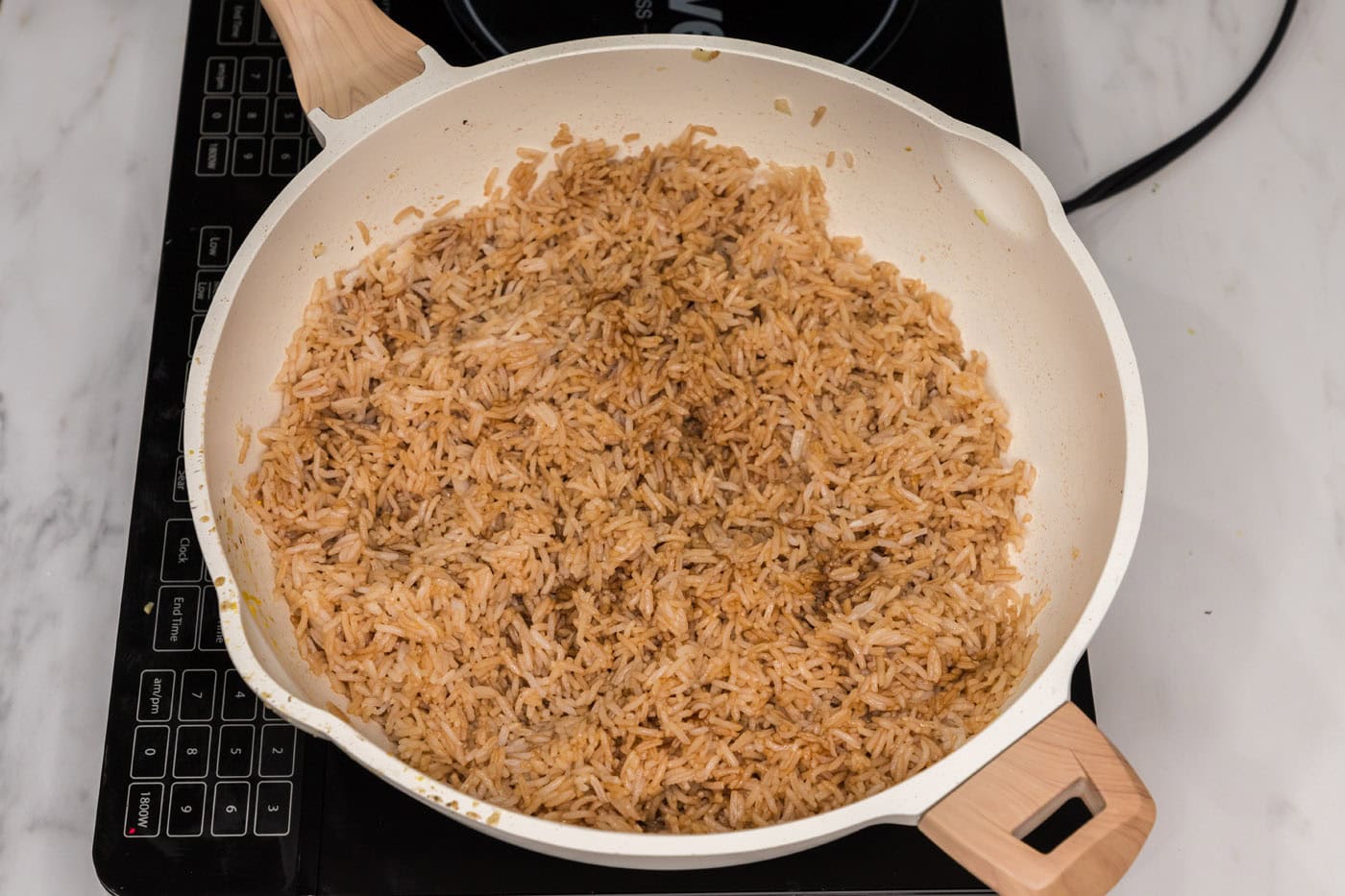 soy sauce and oyster sauce mixed with rice in a skillet