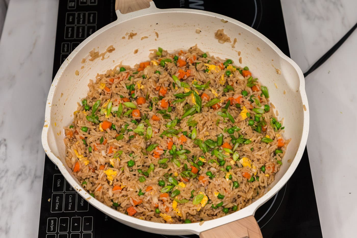 sliced green onions on top of vegetable fried rice in a skillet
