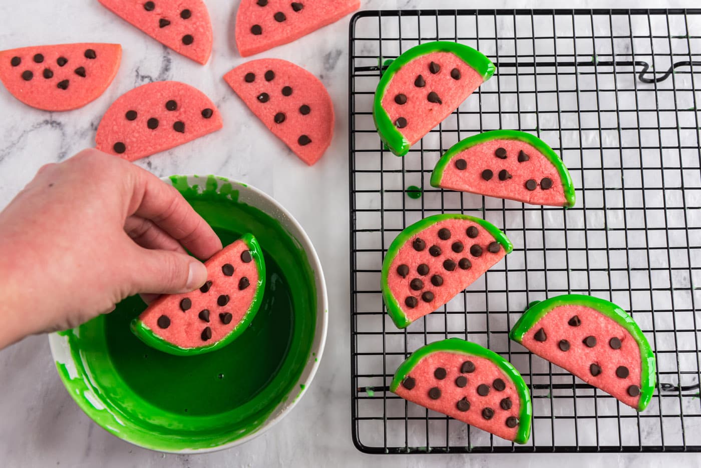 dipping watermelon slice cookies in green glaze