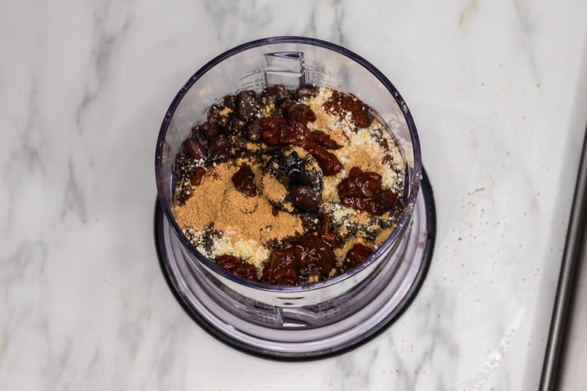 black beans in a food processor with seasonings, chipotle peppers, and soy sauce